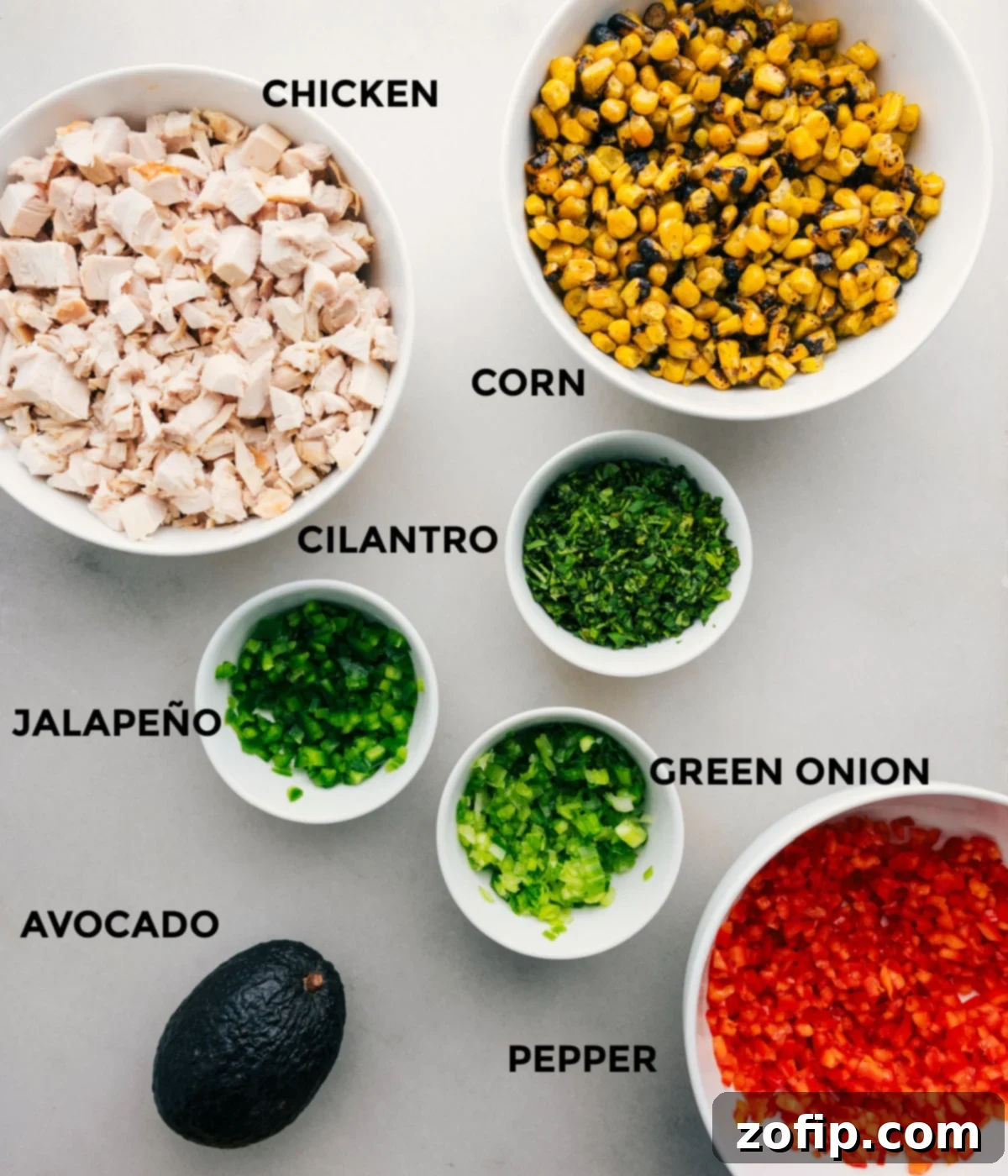 Elote Chicken Salad 4 The ingredients for Mexican street corn chicken salad prepped out for easy assembly, including chicken, corn, avocado, and bell pepper.