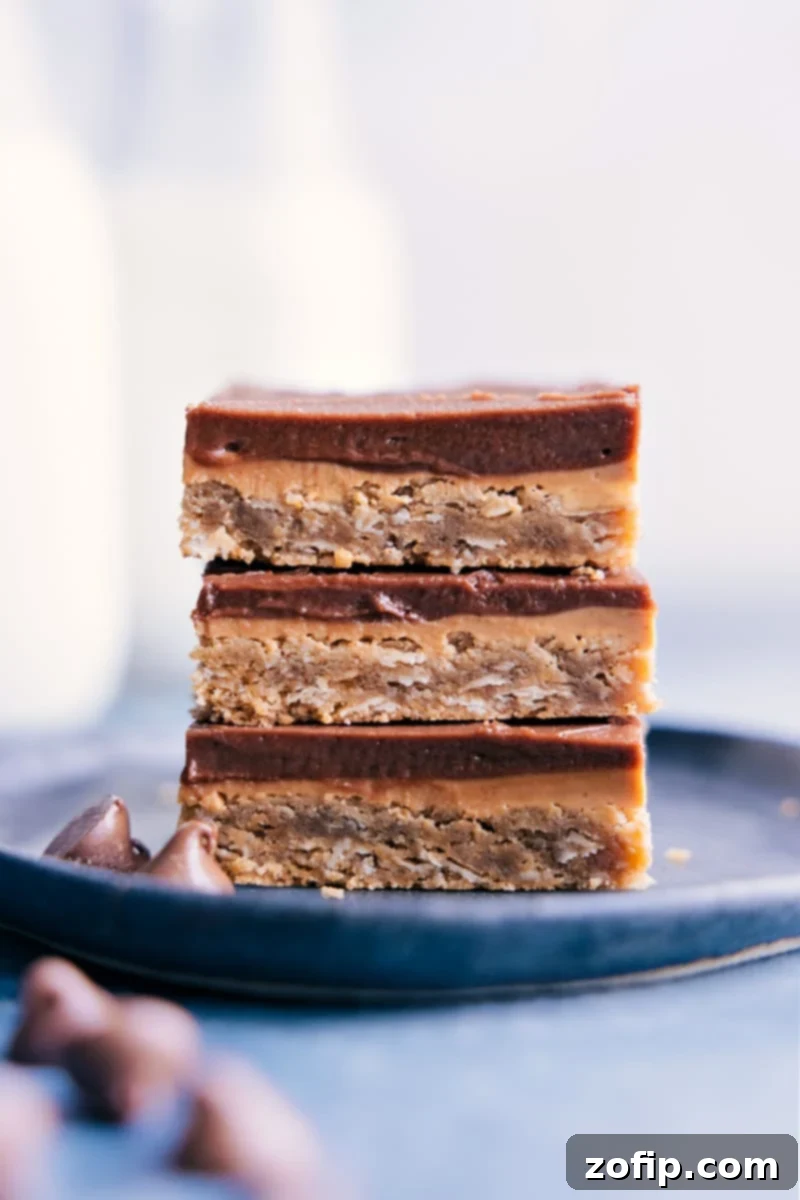 Stacked image of perfectly cut Lunch Lady Peanut Butter Bars, showcasing their distinct layers of oatmeal cookie base, creamy peanut butter, and thick chocolate frosting.