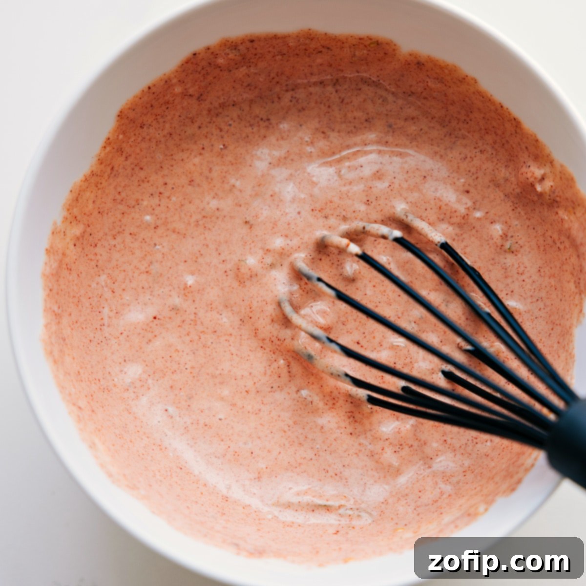 How To Make The Best Burger Sauce For These Burger Bowls A smooth, creamy homemade burger sauce being whisked in a bowl, its rich orange color indicating a perfect blend of ingredients, ready to complement any burger bowl.