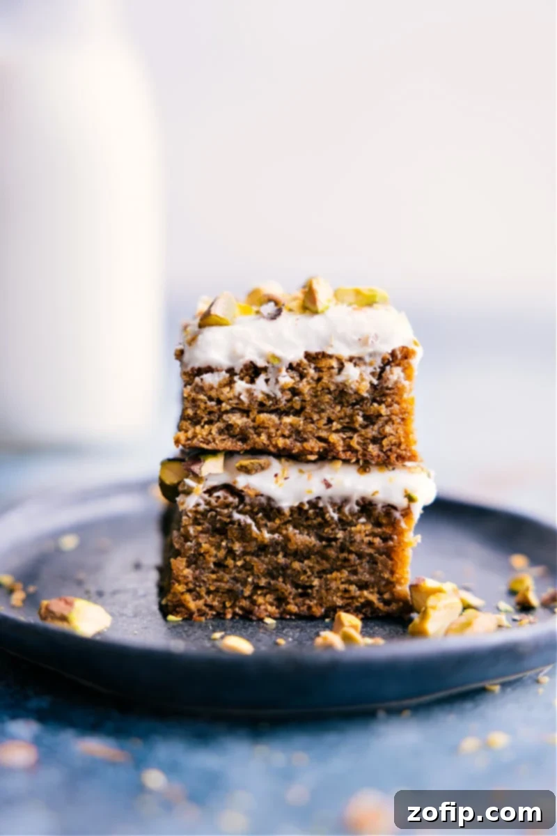 Stacked slices of moist pistachio cake with creamy frosting and chopped pistachios on top, ready to be enjoyed.