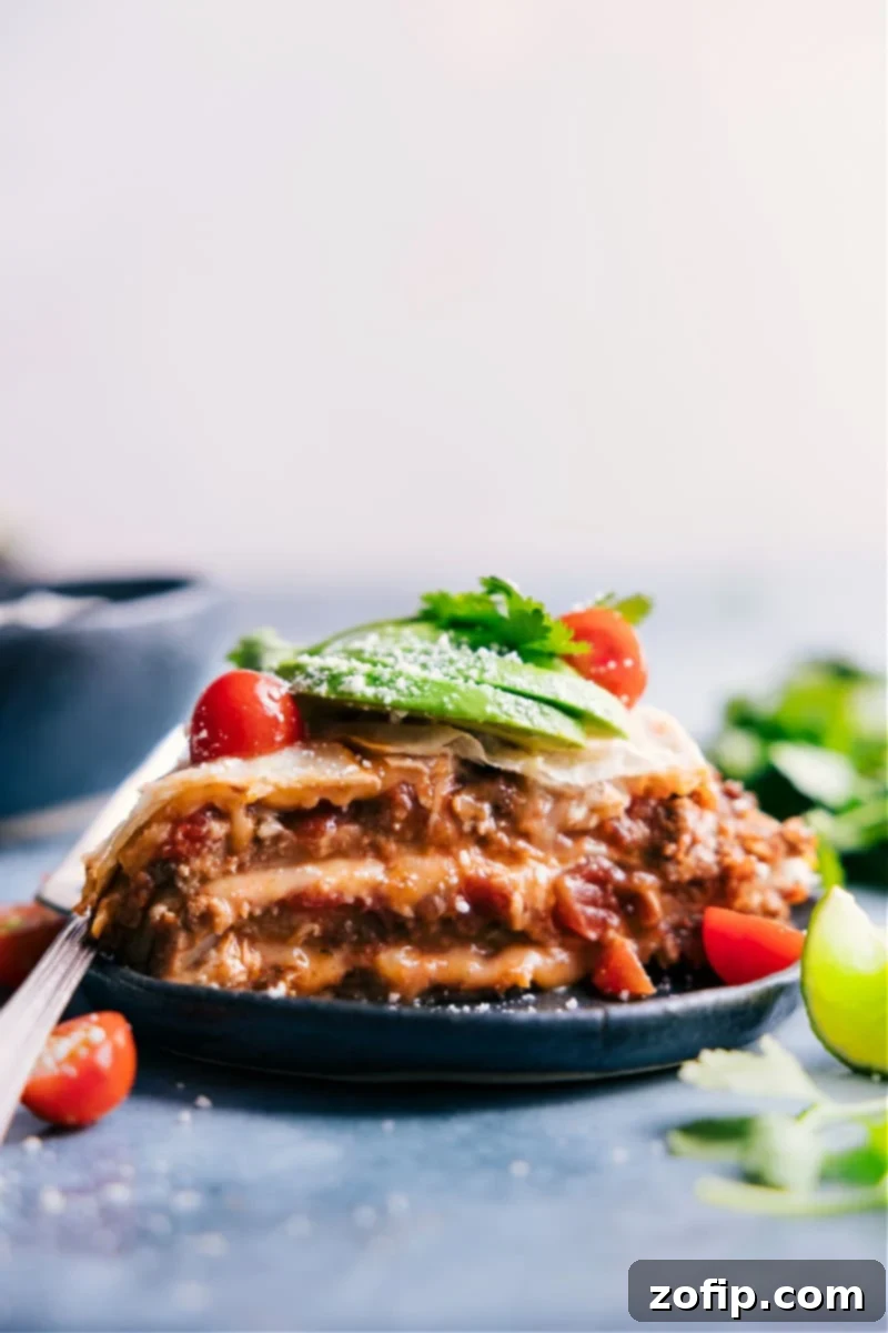 This simple Tortilla Pie layers tortillas with creamy refried beans, taco-seasoned beef, saucy salsa, and plenty of melty cheese. Layer this pie like a lasagna, bake it, and add all your favorite taco toppings! Recipe via ChelseasMessyApron #dinner #quick #easy #simple #best #familyfriendly #kidfriendly #tortilla #pie A slice of golden-brown Tortilla Pie, brimming with refried beans, taco beef, salsa, and melted cheese, served on a plate with fresh toppings like cilantro and sour cream.