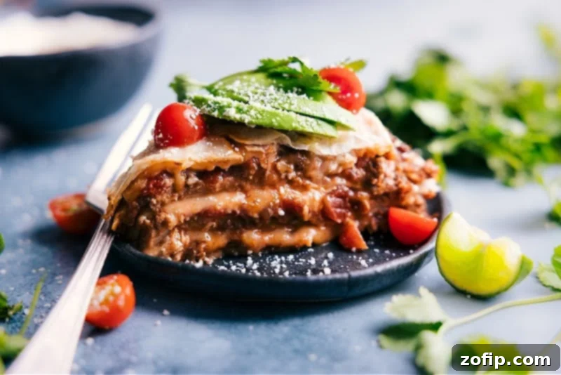 Our favorite Tortilla Pie layers tortillas with creamy refried beans, taco-seasoned beef, saucy salsa, and plenty of melty cheese. Layer this pie like a lasagna, bake it, and add all your favorite taco toppings! Recipe via ChelseasMessyApron #dinner #quick #easy #simple #best #familyfriendly #kidfriendly #tortilla #pie A perfectly baked slice of Tortilla Pie on a white plate, showcasing its distinct layers of tortilla, beans, beef, salsa, and cheese, garnished with fresh cilantro.