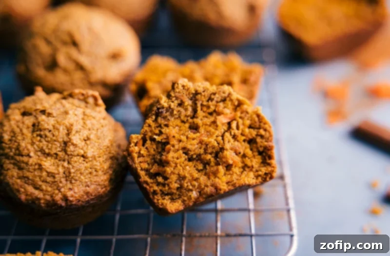 Moist and Flavorful Healthy Carrot Muffins: A perfect gluten-free, dairy-free, refined sugar-free treat. A beautifully baked healthy carrot muffin, cut in half to reveal its moist, spiced interior, studded with visible carrot pieces. It sits on a wooden surface.