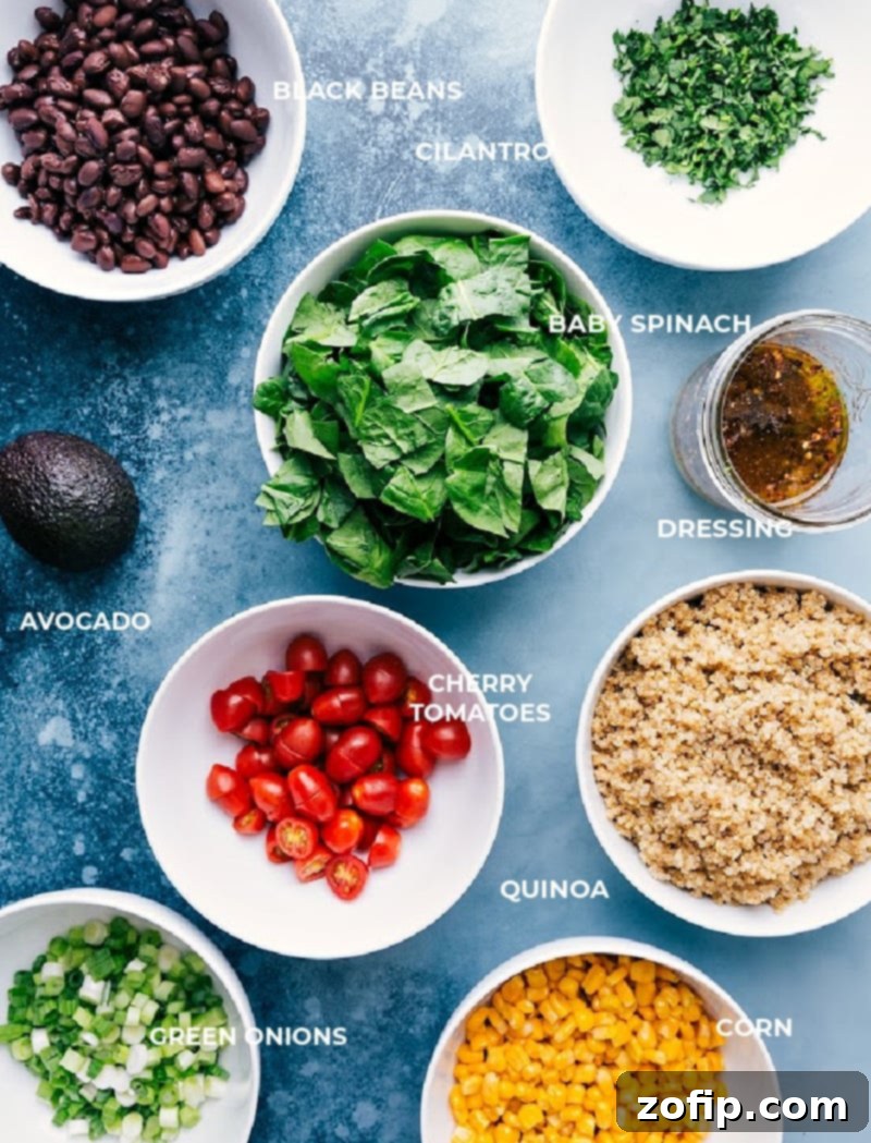 A bright and vibrant overhead shot of all the fresh ingredients for the Quinoa and Veggie Salad laid out, including spinach, corn, black beans, cherry tomatoes, green onions, cilantro, and limes.