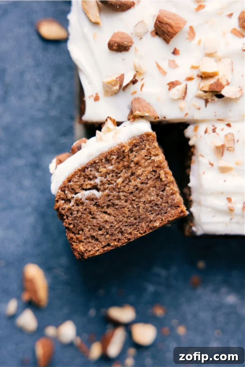 A slice of Healthy Banana Cake with cream cheese frosting and a banana chip on top, showcasing its moist texture.