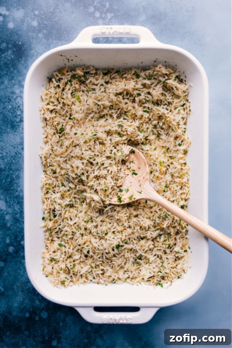 Easy & Fresh Baked Lemon Rice Recipe - Perfectly Fluffy Freshly fluffed baked Lemon Rice, garnished with parsley and lemon zest, served in a ceramic baking pan, ready to be enjoyed.