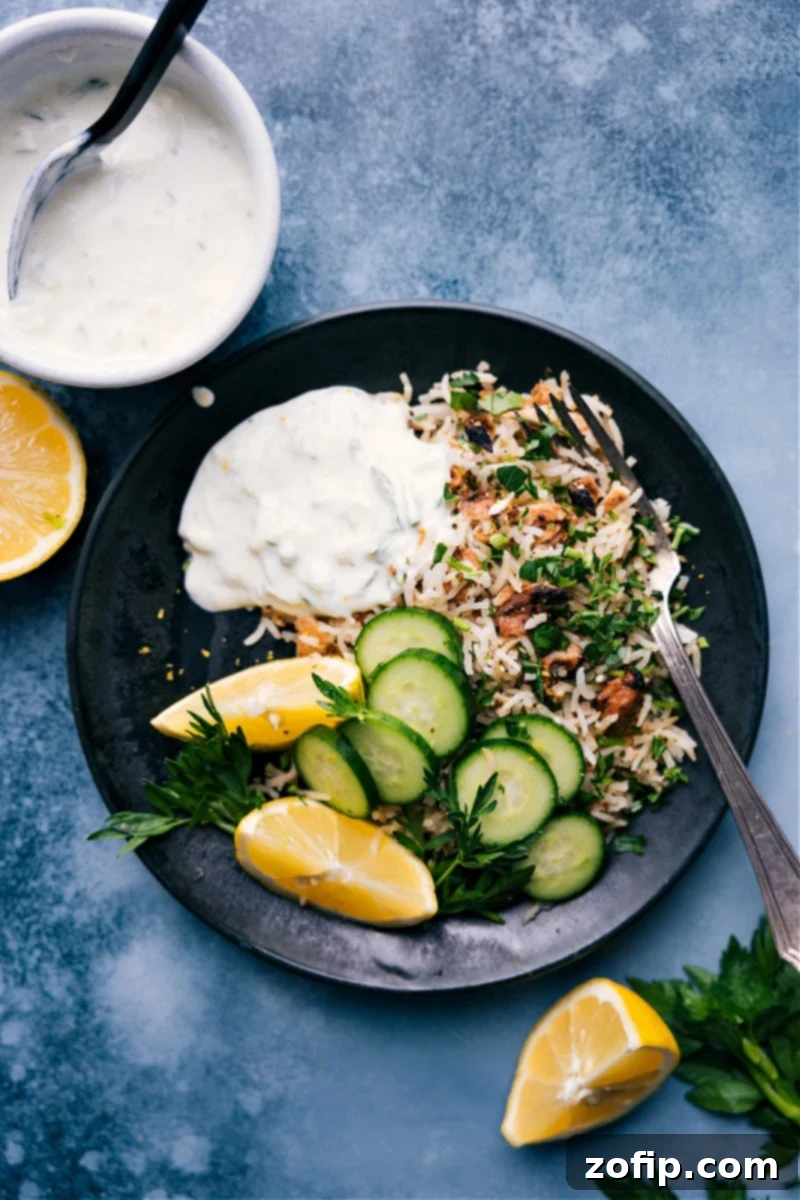 Delicious Lemon Rice Served with Tzatziki and Fresh Sides A vibrant plate of fluffy Lemon Rice garnished with fresh parsley and lemon slices, served alongside a creamy tzatziki sauce, crisp cucumber slices, and warm pita bread.
