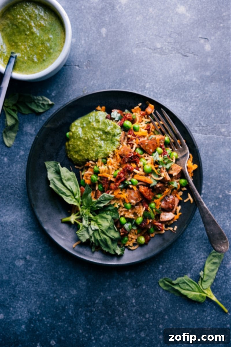 A beautiful presentation of Pesto Rice, served in a bowl with a generous side of fresh basil pesto for personalized garnish.
