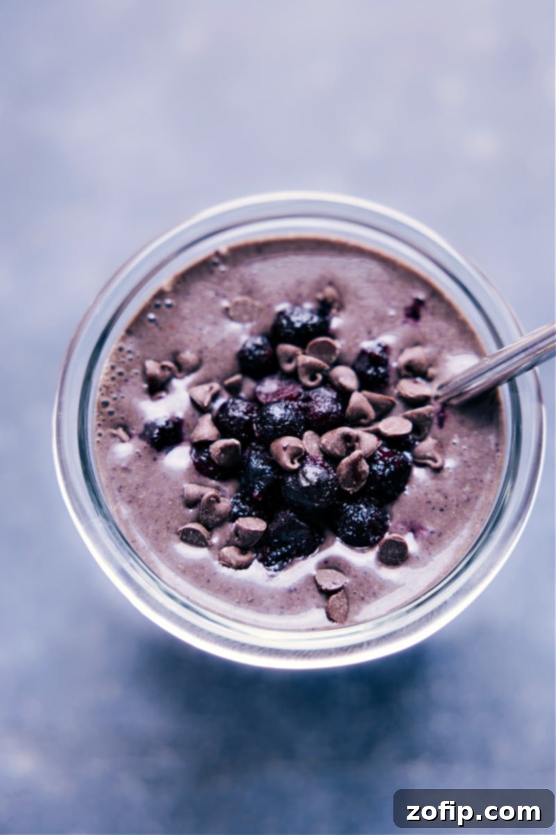 Overhead view of a Chocolate Blueberry Smoothie in a glass with fresh blueberries and chocolate shavings