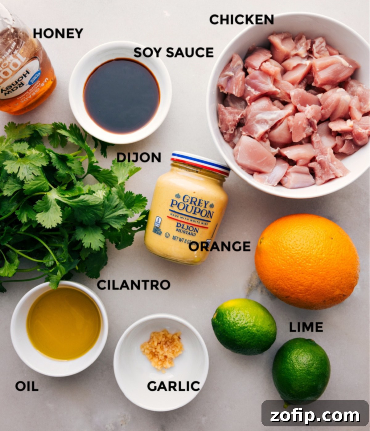 All the fresh ingredients for the Citrus Chicken Marinade are neatly arranged: chicken, soy sauce, honey, Dijon mustard, whole oranges, fresh cilantro, garlic cloves, and limes, ready for preparation.
