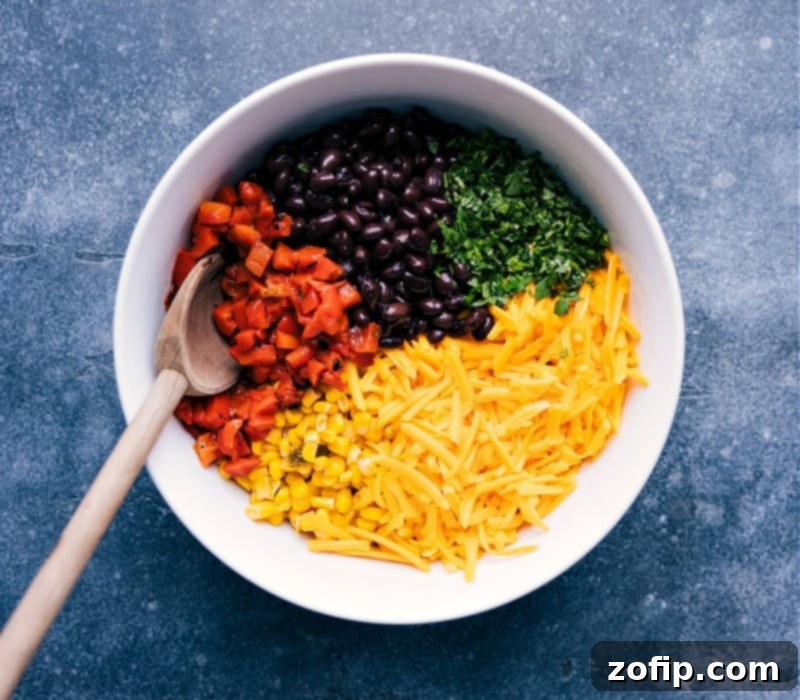 A vibrant bowl containing the ingredients for black bean quesadillas: black beans, corn, diced roasted red peppers, shredded Cheddar cheese, and fresh cilantro.