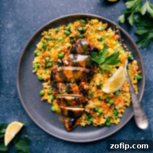 Final plated Moroccan Chicken with couscous and apricot sauce, garnished with parsley and lemon