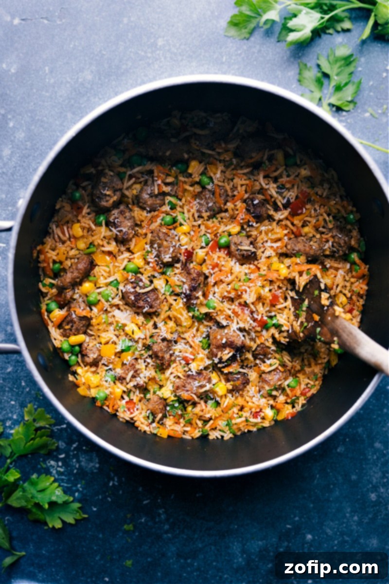 Overhead image of the meatballs and rice, garnished with fresh herbs, showcasing tender mini meatballs, fluffy rice, and colorful vegetables in a large pot.
