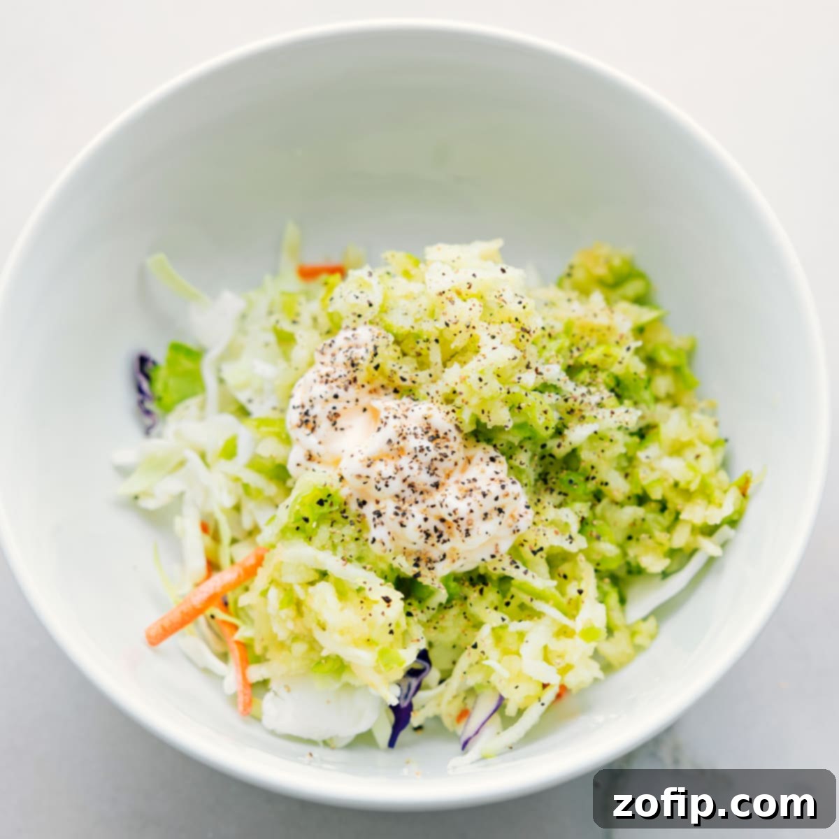 The vibrant apple coleslaw mixture being expertly tossed in a bowl, its ingredients perfectly combined and ready to fill these delicious and healthy turkey wraps.