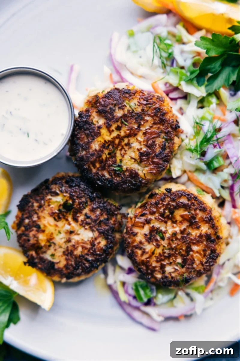 Delicious Tuna Patties with a perfect crisp texture and soft interior, ready for a family dinner. Served with fresh coleslaw and tangy tartar sauce. Overhead image of Crispy Tuna Patties served with coleslaw and tartar sauce