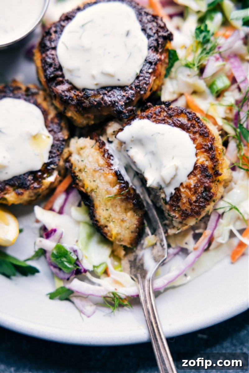 A complete and delicious meal: Tuna Patties perfectly presented on crisp coleslaw, generously topped with tangy tartar sauce. Overhead image of Tuna Patties served on a bed of fresh coleslaw with tartar sauce drizzled on top