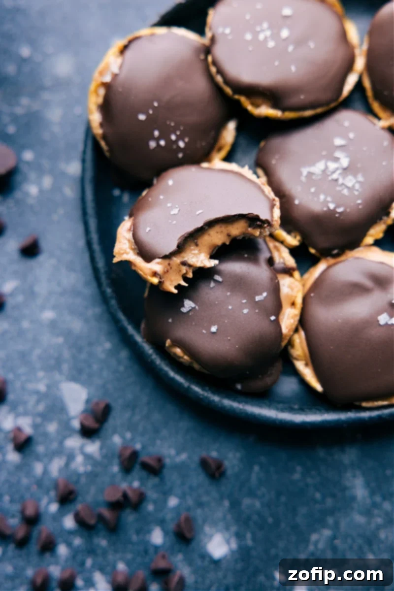 A plate of freshly prepared Rice Cakes with Peanut Butter and Chocolate, ready to be enjoyed. Each mini rice cake features a layer of creamy peanut butter, a hardened dark chocolate shell, and a sprinkle of flaky sea salt, showcasing its irresistible appeal as a quick and satisfying snack.
