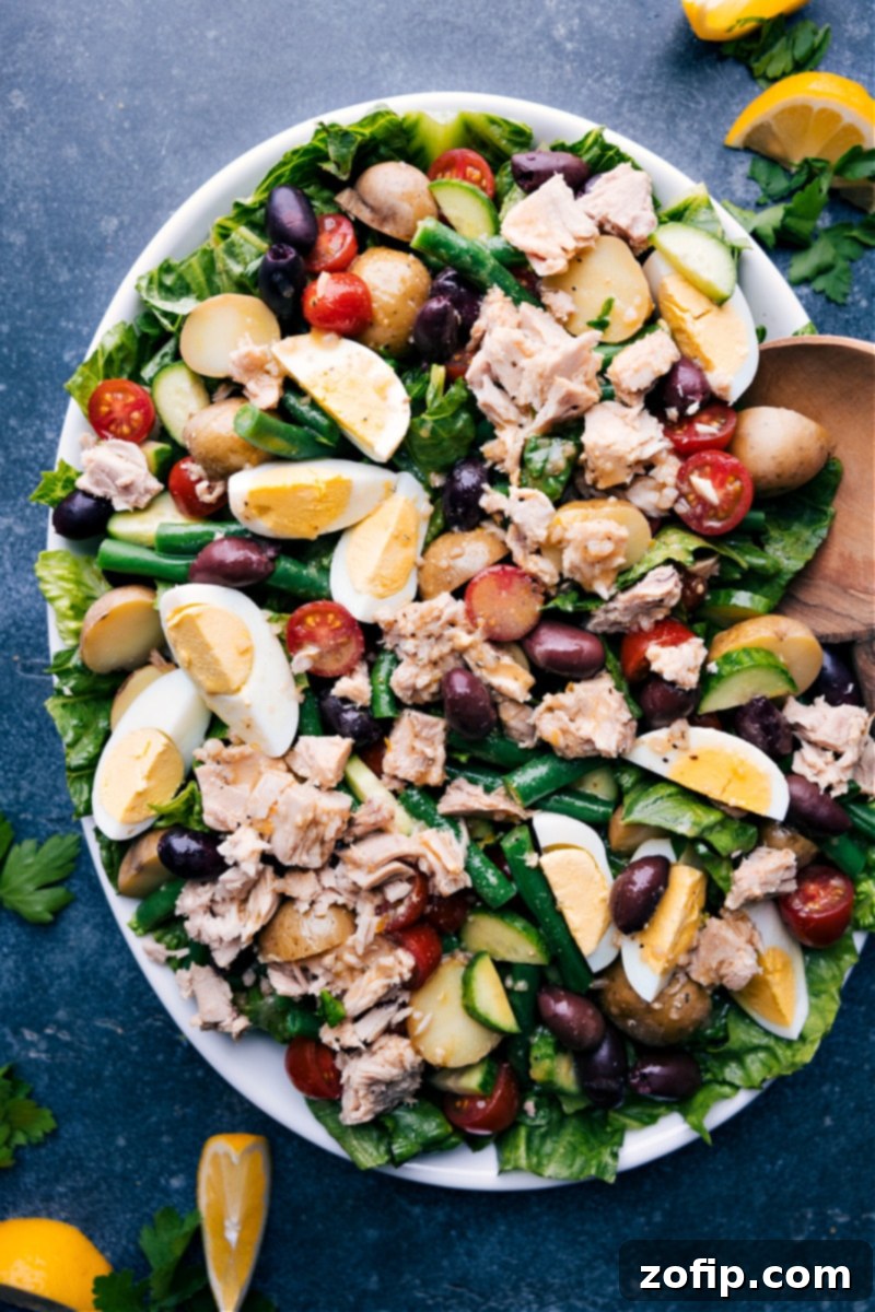 Vibrant Tuna Nicoise 7 A vibrant overhead image of a fully dressed Tuna Niçoise Salad on a platter, perfectly arranged with all components and ready to be enjoyed as a fresh and healthy meal.