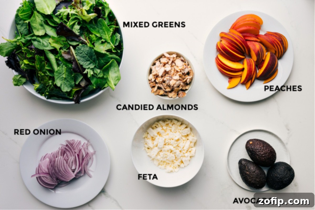 All the fresh ingredients for the peach salad laid out and prepped: mixed greens, vibrant red onions, creamy feta, golden candied almonds, perfectly ripe avocado slices, and juicy peach wedges, ready for assembly.