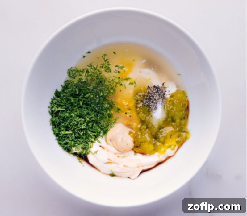 Another process shot showing the final ingredients being added to the bowl and mixed, creating a smooth and creamy homemade Tartar Sauce.