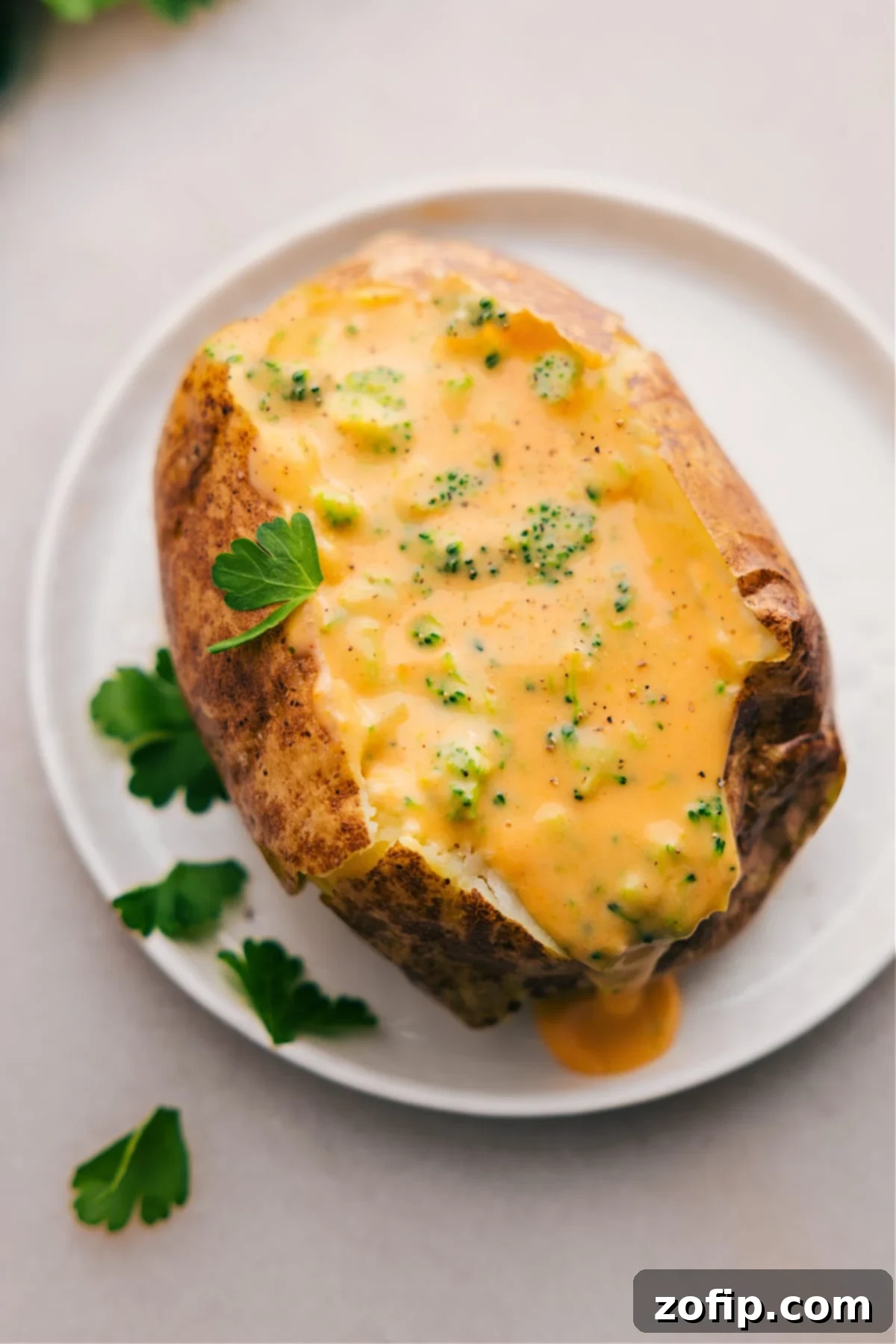 The Best Broccoli And Cheese Baked Potatoes: A Hearty and Delicious Meal Two fluffy baked potatoes on a plate, cut open and generously topped with a vibrant, creamy broccoli and cheese sauce, ready to be enjoyed.