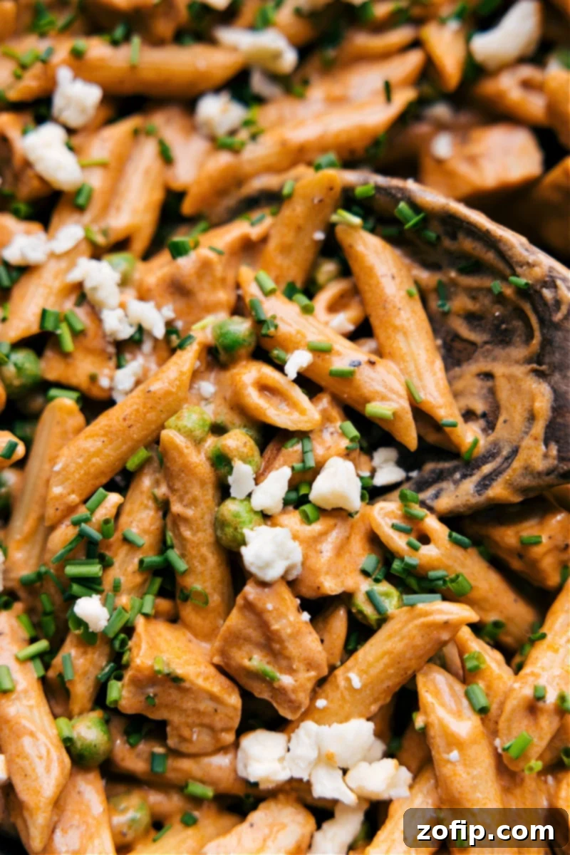 This Buffalo Chicken Pasta packs a serious punch of flavor and is so easy to make thanks to some ingredient short-cuts. Quell your buffalo chicken cravings in under 30 minutes and all while getting loads of protein in! #dinner #quick #easy #simple #familyfriendly #kidfriendly #buffalo #chicken #pasta Overhead shot of a vibrant bowl of Buffalo Chicken Pasta, garnished with fresh green onions and blue cheese crumbles.