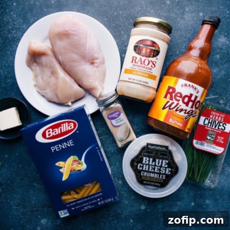 This Buffalo Chicken Pasta packs a serious punch of flavor and is so easy to make thanks to some ingredient short-cuts. #dinner #quick #easy #simple #familyfriendly #kidfriendly #buffalo #chicken #pasta Selection of fresh ingredients laid out for making Buffalo Chicken Pasta, including chicken breasts, pasta, sauces, and garnishes.