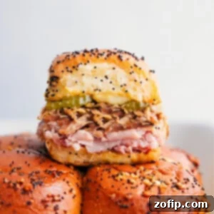 A single Cuban Slider showing layers of meat, cheese, and pickles on a sweet roll, ready to be eaten.