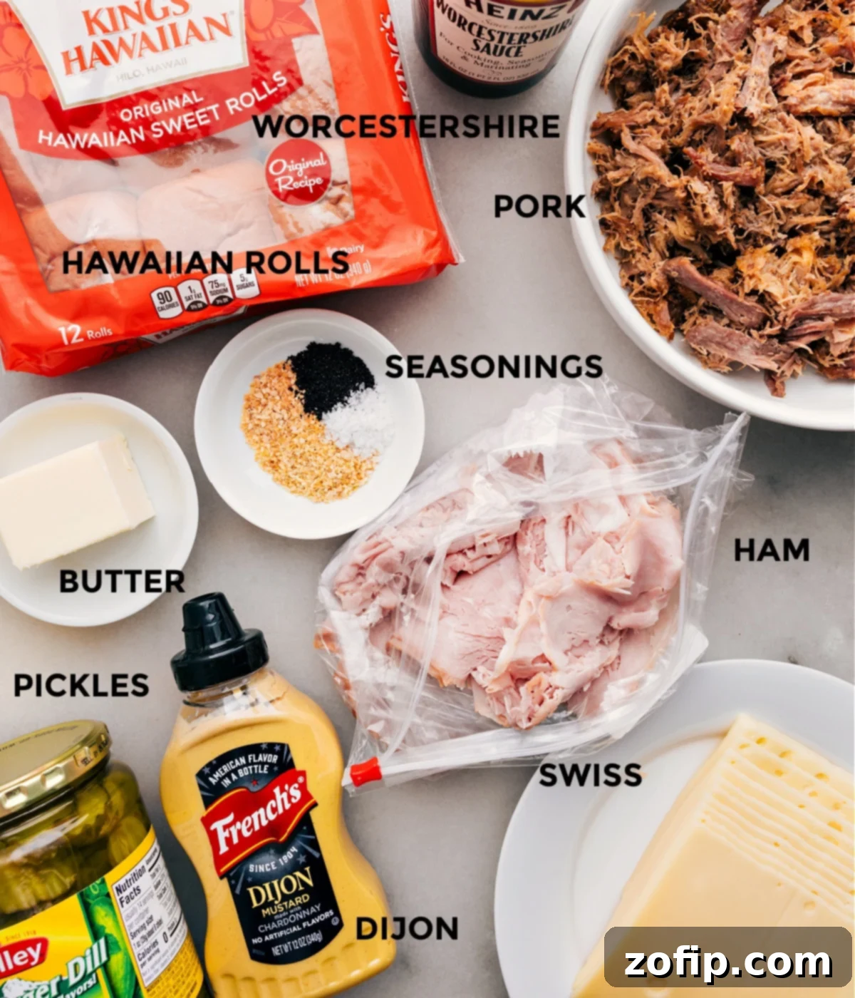 All the fresh ingredients laid out and prepped for assembling flavorful Cuban Sliders: Hawaiian rolls, Swiss cheese, shredded pork, ham, dill pickles, and mustard sauce ingredients.