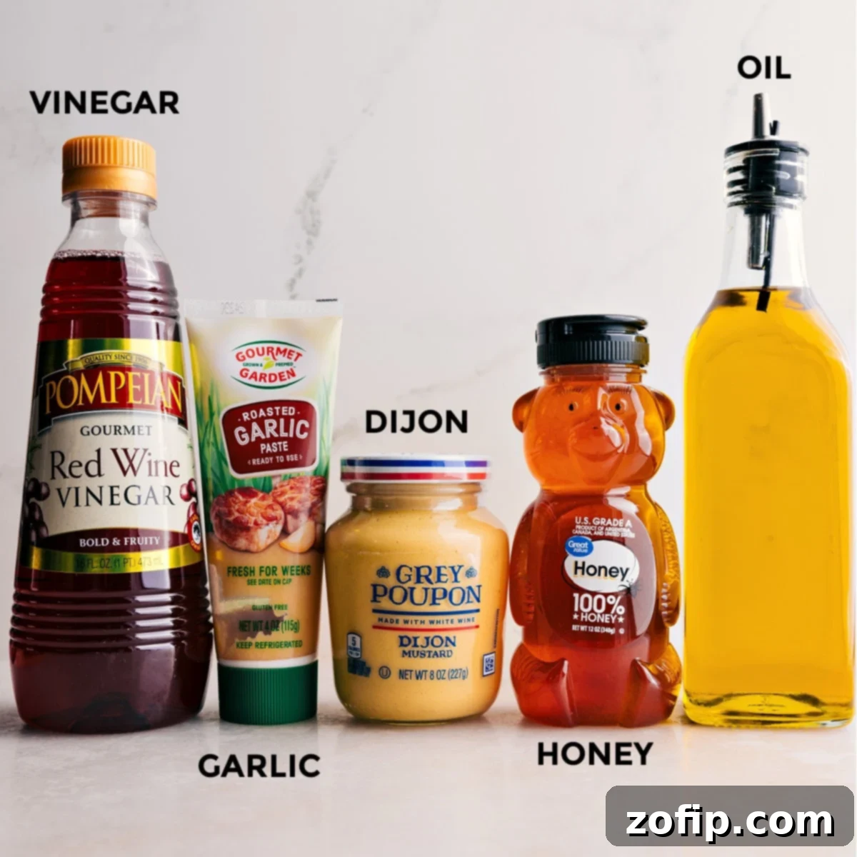 All the ingredients for the quick and simple dressing used in this everyday salad recipe prepped out including honey, oil, dijon mustard, garlic, and red wine vinegar.