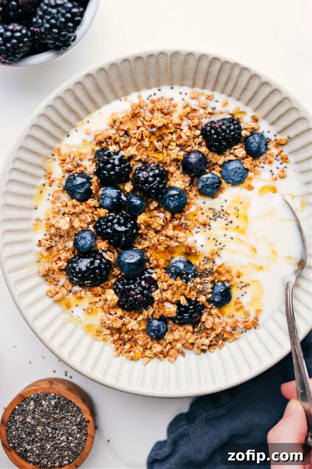 Easy Homemade Granola Recipe served over creamy yogurt with vibrant fresh berries, showcasing its crunchy texture and appeal.