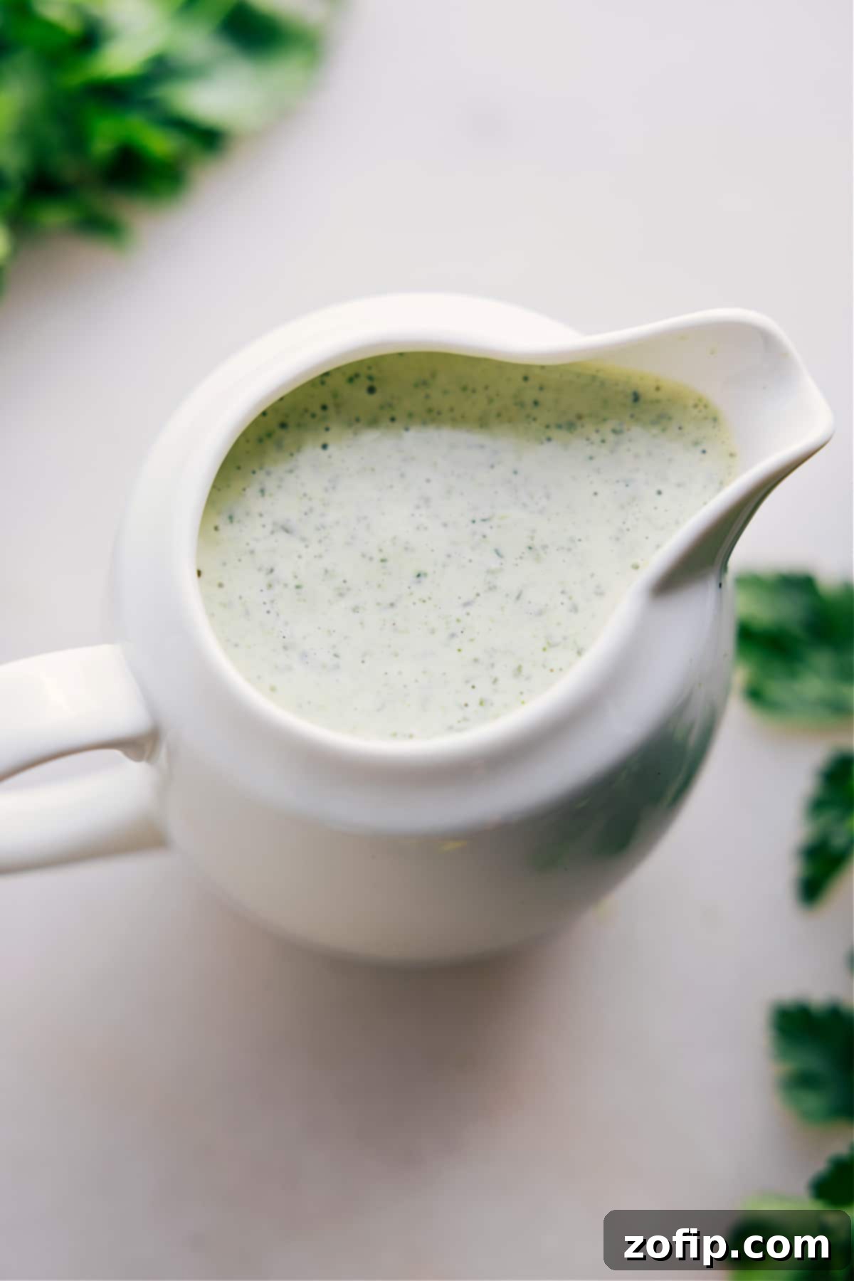 A jar filled with homemade Green Goddess Dressing, perfect for drizzling over fresh salads or as a delightful dip for vegetables.