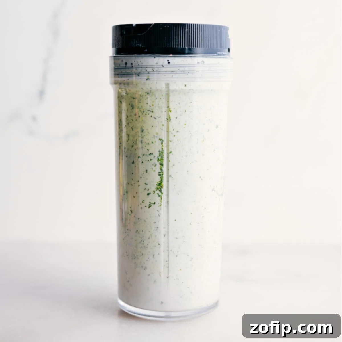 The vibrant green goddess dressing is smoothly blended in a blender jar, showcasing its creamy texture and rich color, ready to be served or chilled.