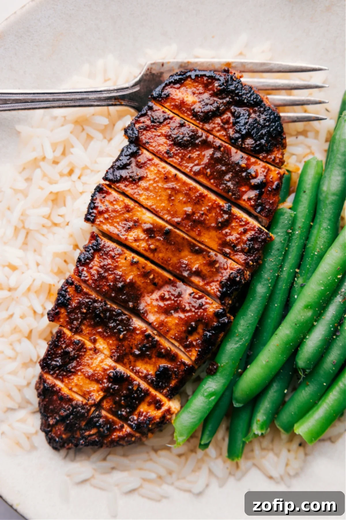 Easy Blackened Chicken recipe served over a bed of fluffy white rice with vibrant green beans on the side, showcasing a complete and balanced meal.