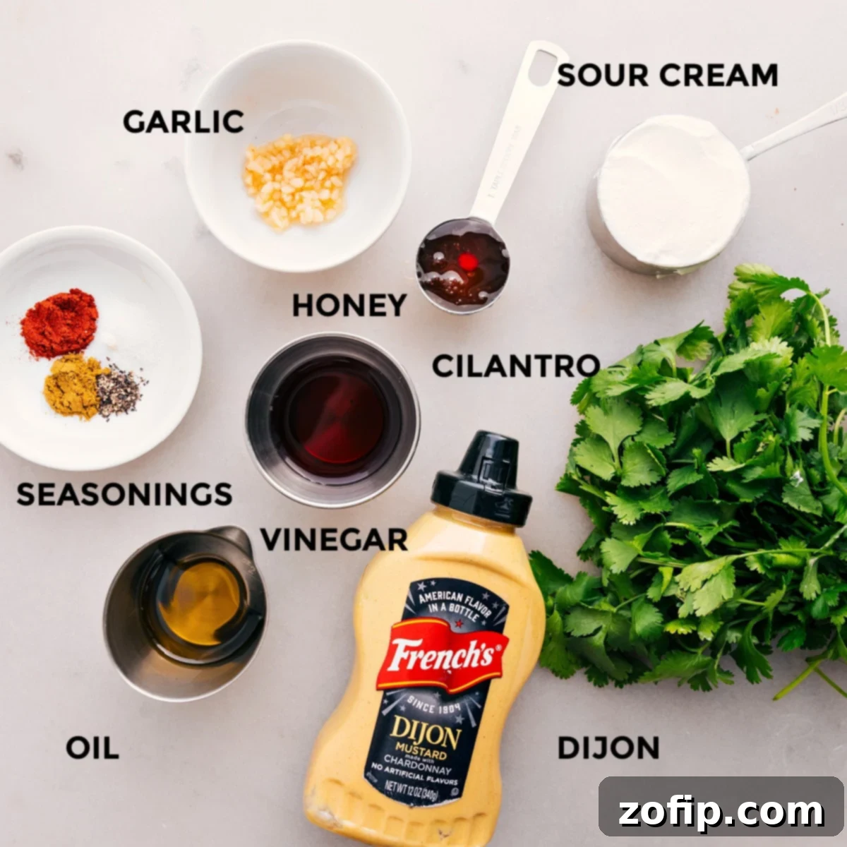 All the dressing ingredients for this sweet potato black bean salad are prepped and ready for easy assembly, including fresh cilantro, red wine vinegar, olive oil, honey, Dijon mustard, spices, and sour cream.