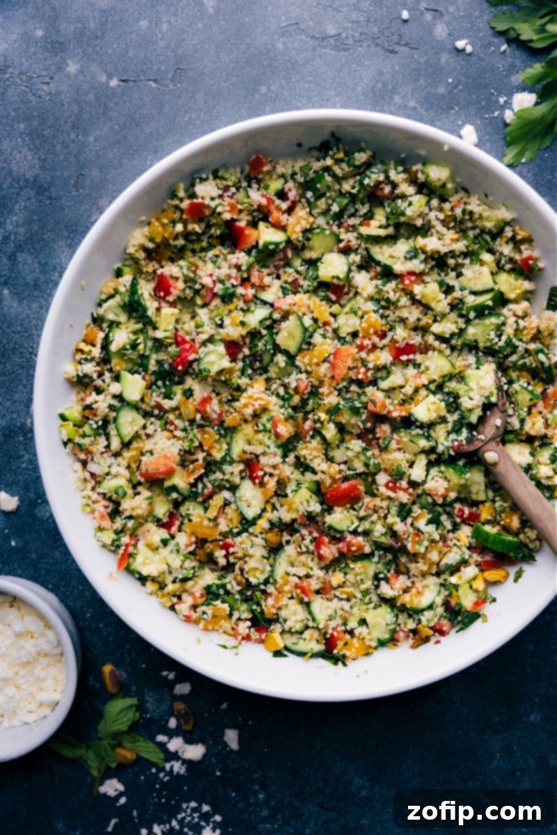 Overhead view of a vibrant Bulgur Salad in a ceramic bowl, garnished with fresh mint and lemon slices, inviting you to taste its rich flavors.