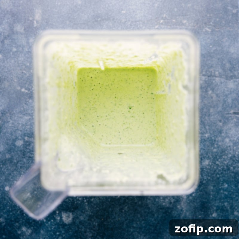 Healthy Cilantro-Lime Dressing is thick, creamy, and ridiculously flavorful! It's hard to believe this sauce is naturally dairy-free, gluten-free, and vegan! A must-try recipe via chelseasmessyapron #salad #dip #best #easy #simple #healthy #cilantrolime #dressing Process shots showing the cilantro lime dressing after blending, looking smooth and vibrant green in a glass jar.