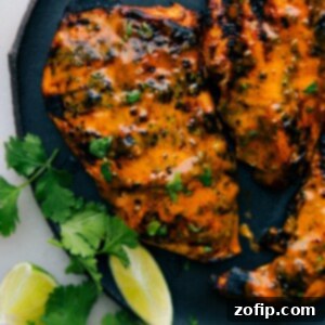 Smoky Chipotle Chicken Marinade 3 Close-up of a perfectly grilled Chipotle Chicken breast, garnished with fresh cilantro and lime wedges.