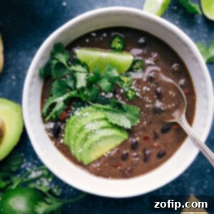 A vibrant bowl of Black Bean Soup, garnished with fresh cilantro and a dollop of sour cream.