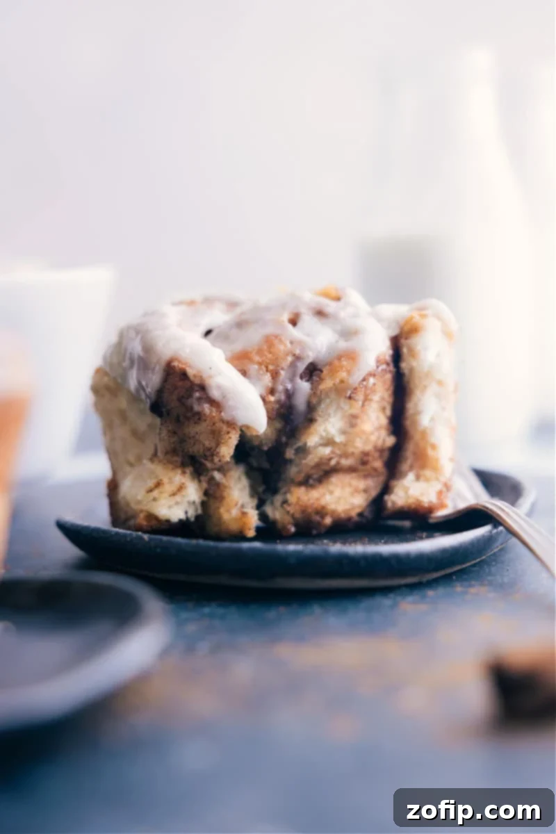 Enjoying the best easy cinnamon roll recipe – a stack of fluffy, frosted cinnamon rolls on a rustic board.