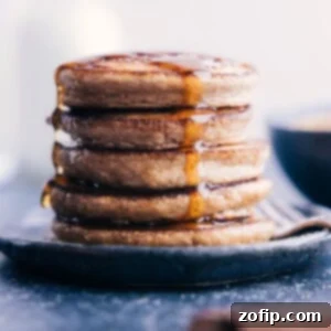 A stack of golden brown applesauce pancakes with syrup and fresh berries