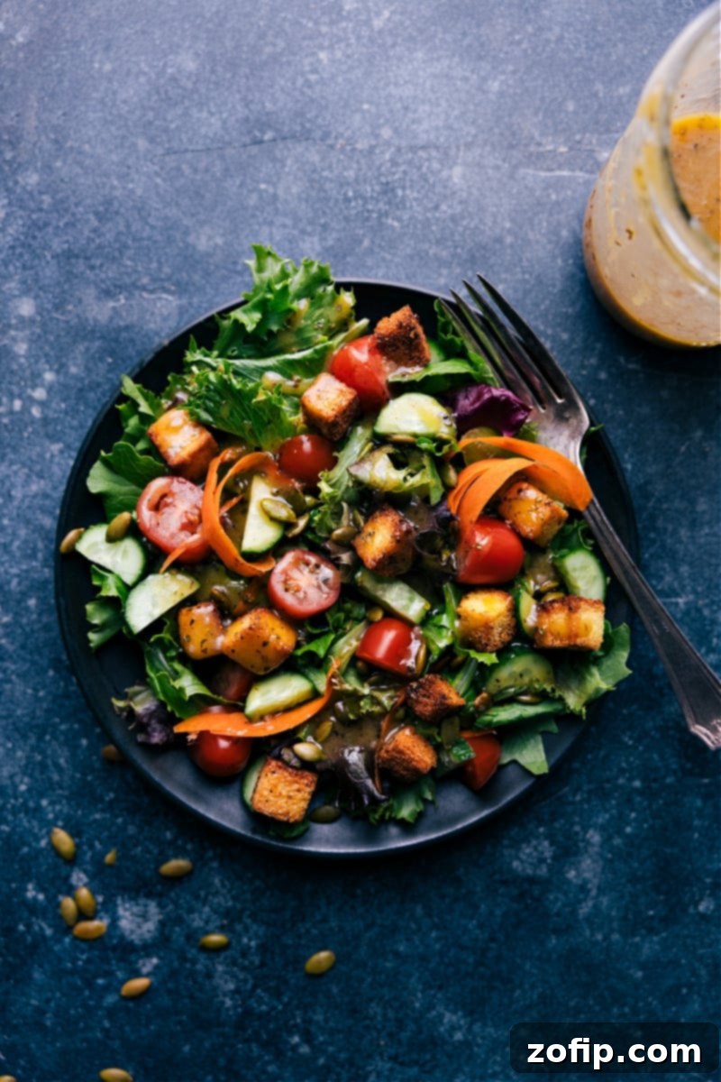 Overhead view of a fresh green salad with homemade vinaigrette dressing drizzled over it, looking vibrant and appetizing.