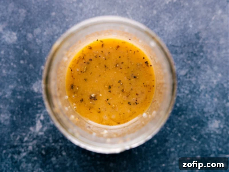 Overhead shot of freshly made vinaigrette in a clear glass cruet, ready to be poured.