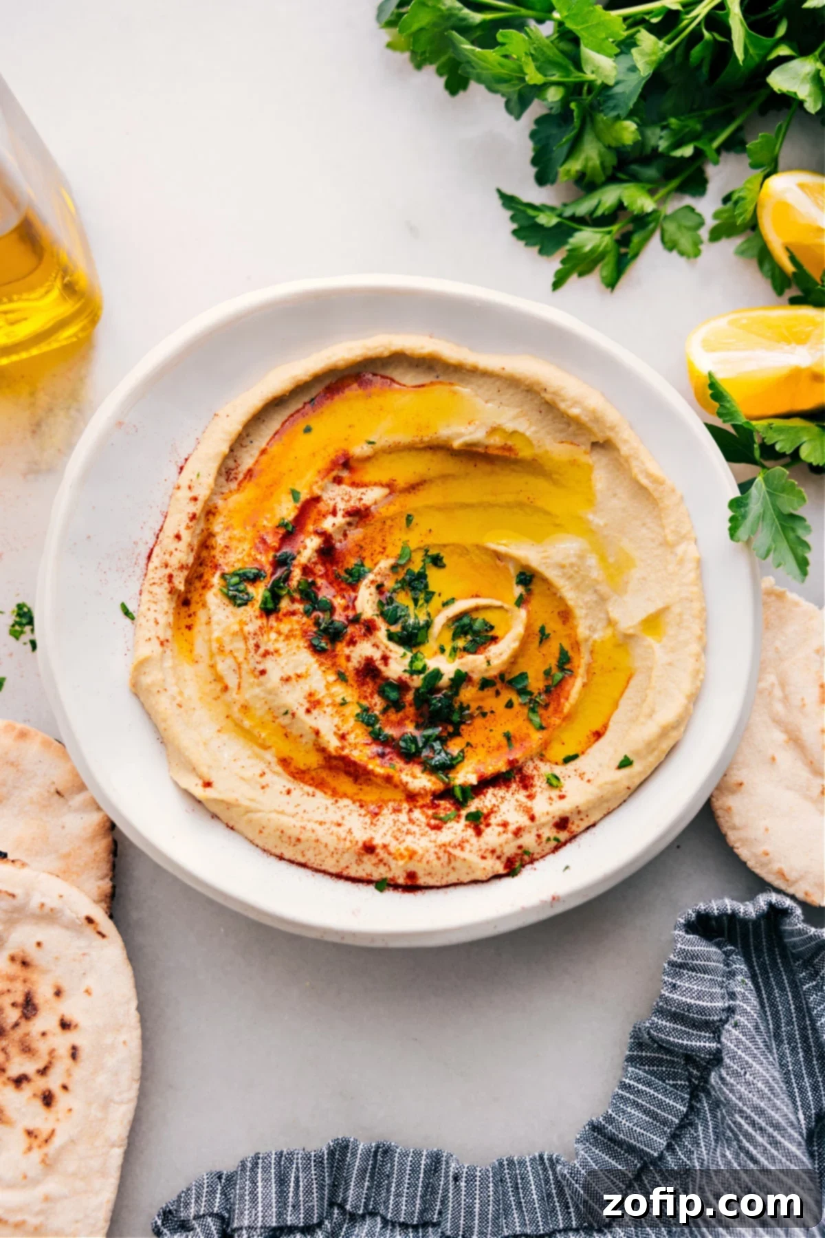 Middle Eastern Hummus Recipe: Rich & Creamy Rich, creamy hummus in a decorative bowl, drizzled with fresh olive oil, sprinkled with paprika and chopped herbs, ready to be enjoyed.