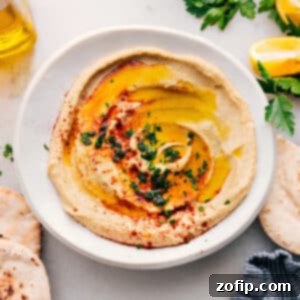 Restaurant Quality Hummus at Home 3 Close-up of freshly prepared, creamy hummus in a white bowl, garnished with olive oil and paprika.