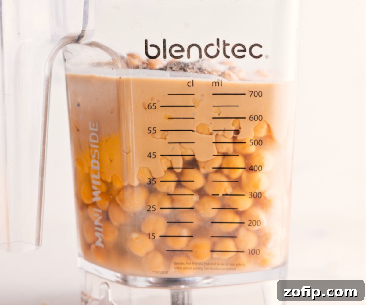 Blending Homemade Hummus for Smooth Perfection All the essential hummus ingredients, including chickpeas, tahini, lemon juice, and garlic, are combined inside a high-powered blender, ready to be transformed into a smooth dip.