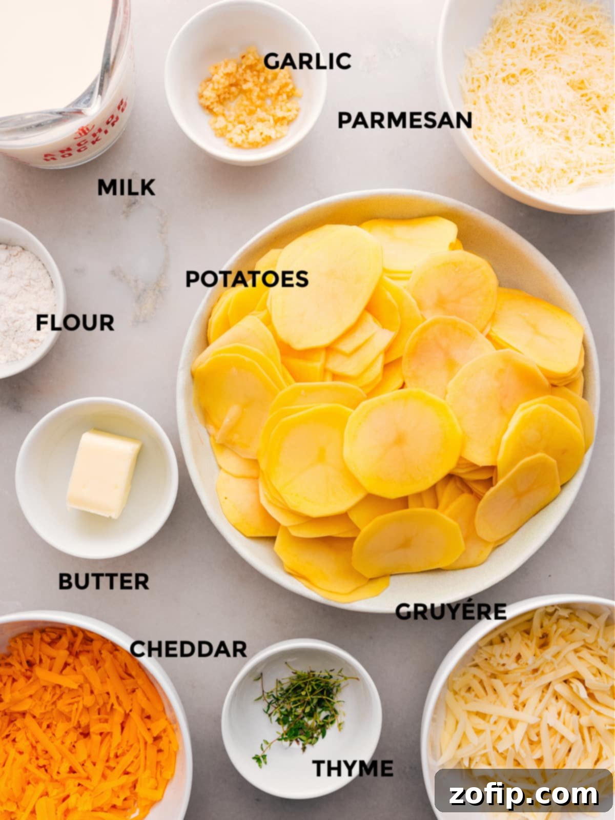 The ingredients for this recipe—Yukon gold potatoes, flour, butter, fresh thyme, a blend of cheeses, whole milk, and minced garlic—are prepped and ready for easy assembly of the creamy au gratin potatoes.