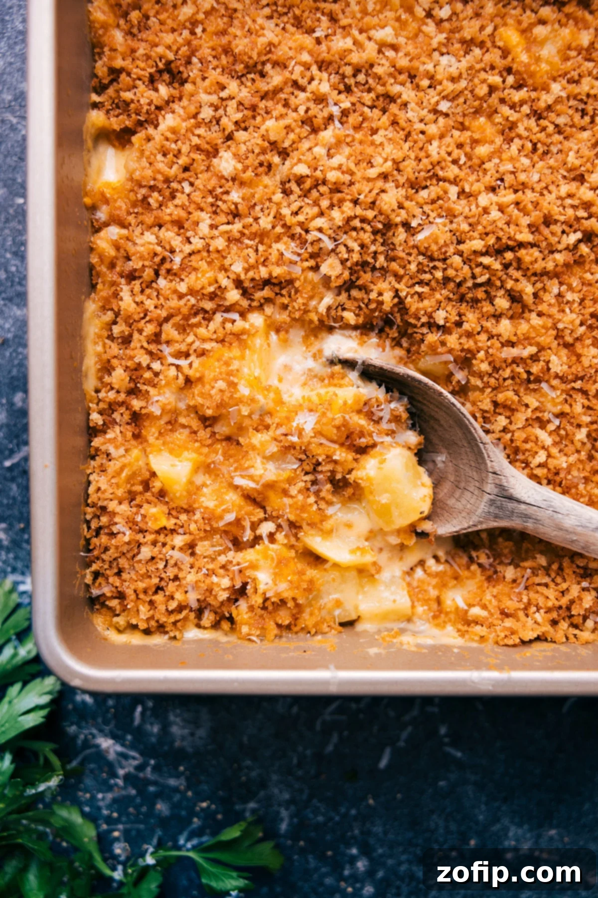 Freshly baked Cheesy Potatoes with a big scoop ready to serve, showing off its golden crust and creamy interior.