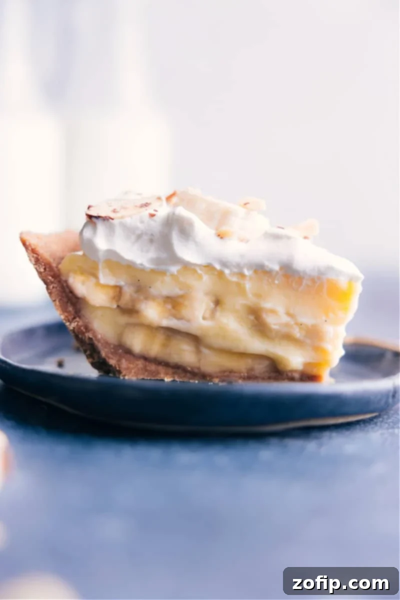 A perfectly sliced homemade Banana Cream Pie, revealing layers of crisp graham cracker crust, sweet fresh banana slices, silky custard, and fluffy whipped cream topping.