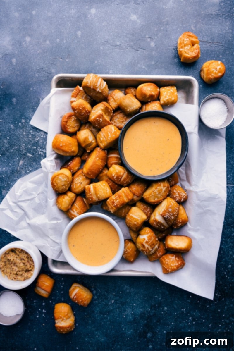 Overhead image of freshly baked Pretzel Bites on a baking sheet, some with salt, some with cinnamon sugar, ready to be dipped